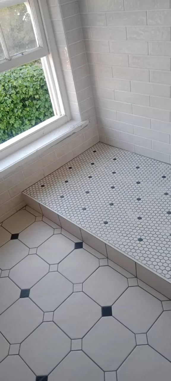 Bathroom wall tiling with mosaic bench and patterned floor tiles near a window