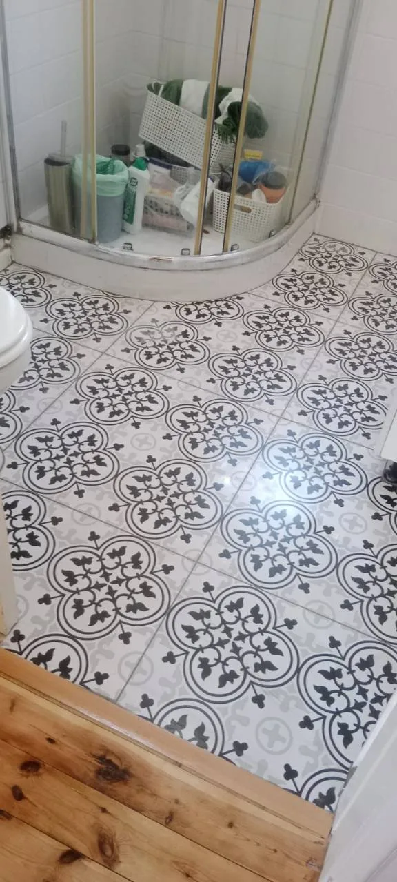 Bathroom floor tiling with patterned grey and black tiles around a shower