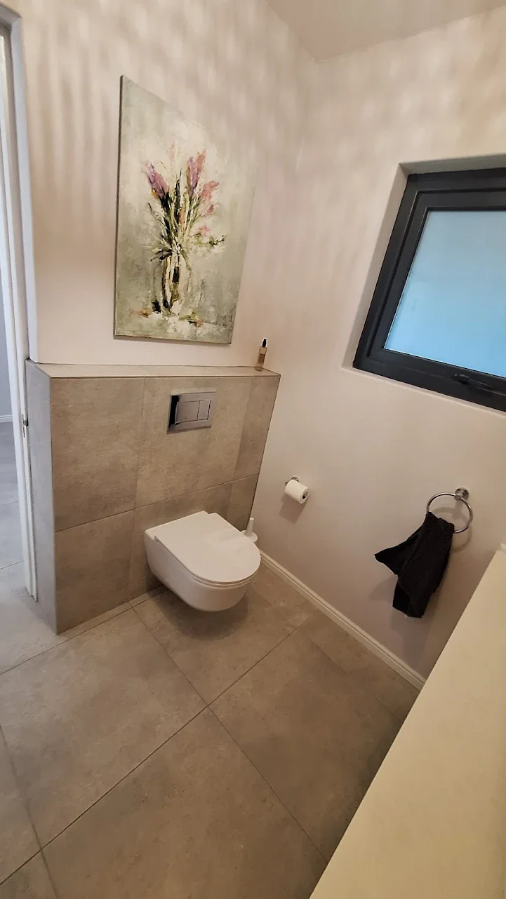 Compact bathroom tiling with wall mounted toilet and clean layout