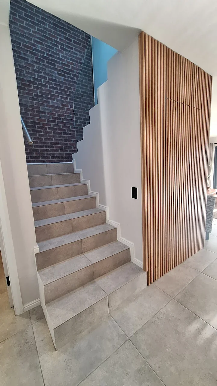 Modern staircase tiling with feature wall and vertical wood panel design