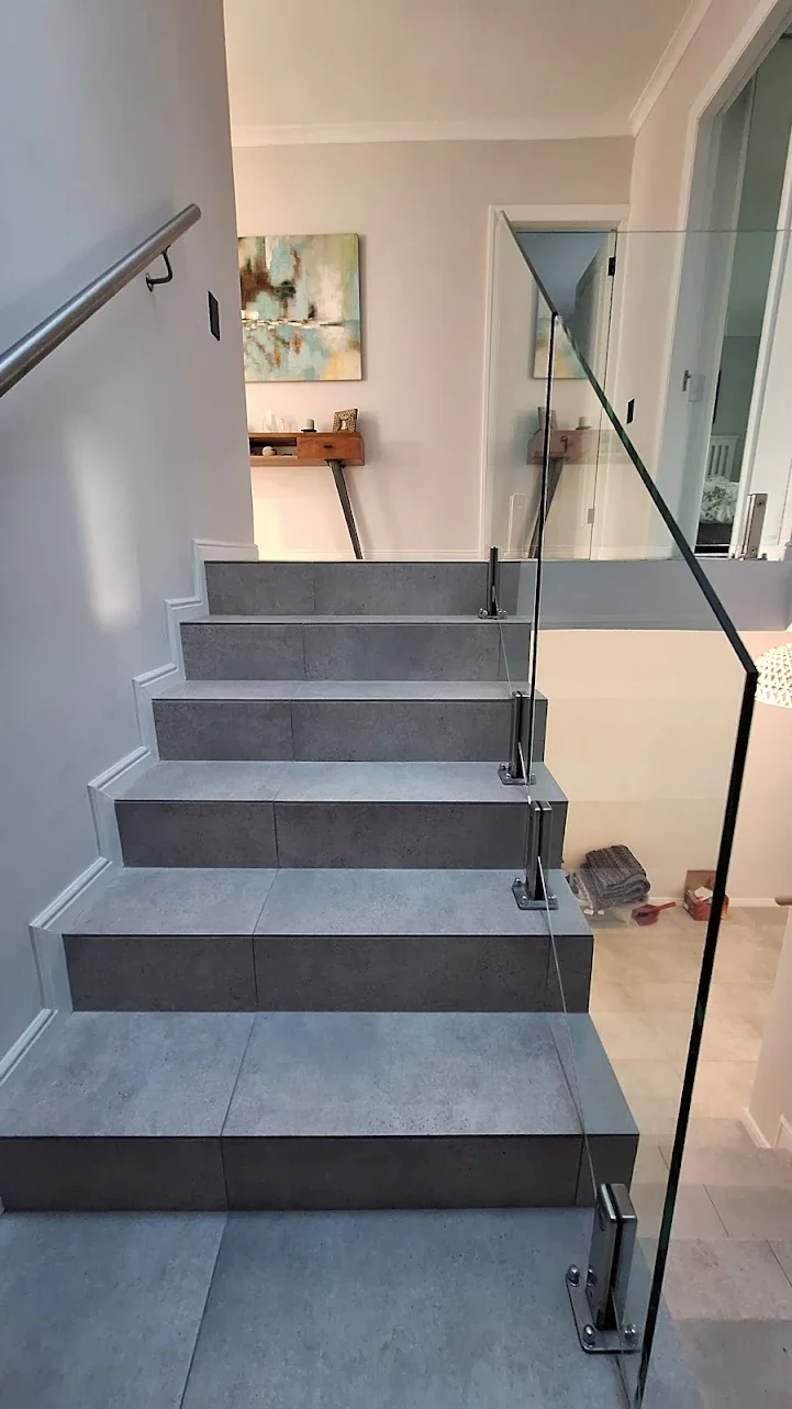 Tiled staircase with glass railing and clean edge finish